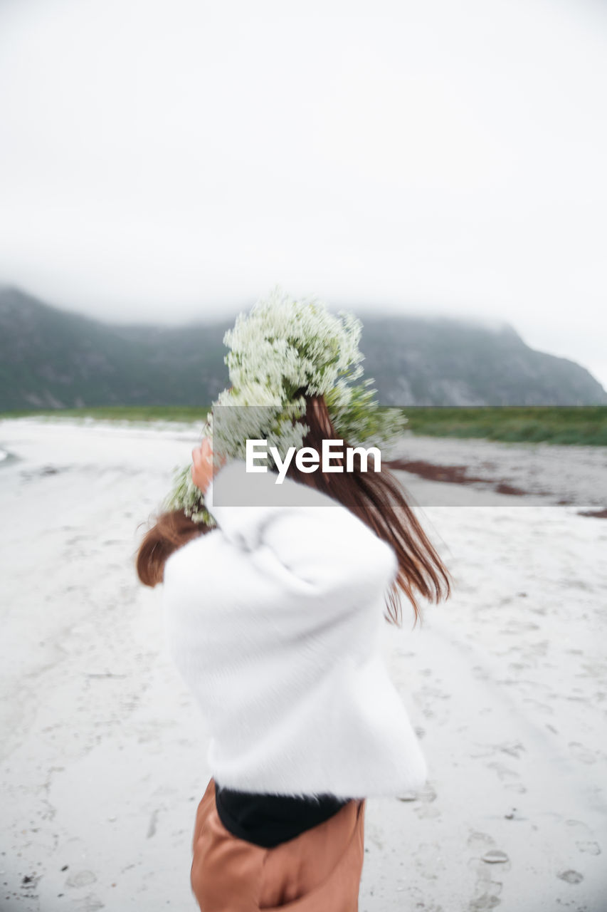 rear view of woman standing at beach against clear sky