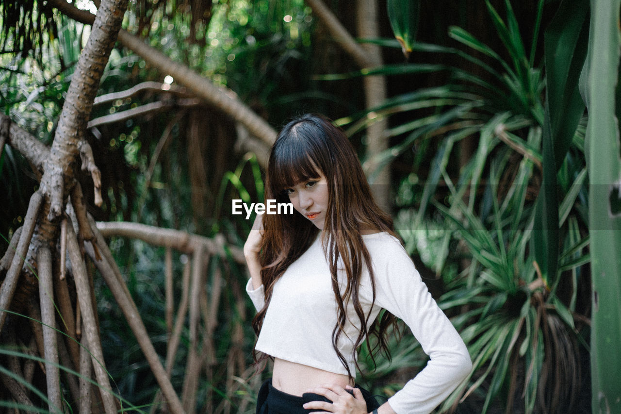 Woman standing by tree in forest