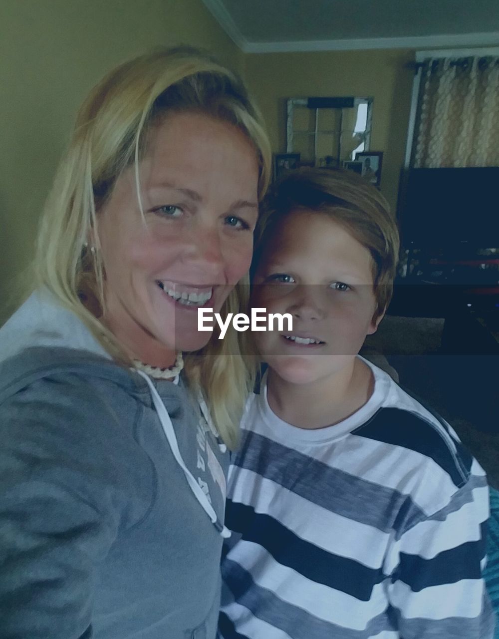 Portrait of happy mother and son standing at home