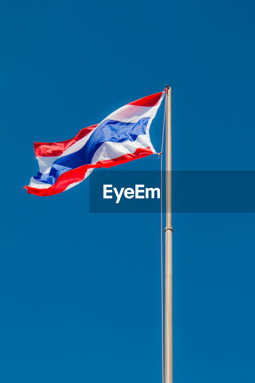 Low angle view of thai flag waving against clear blue sky