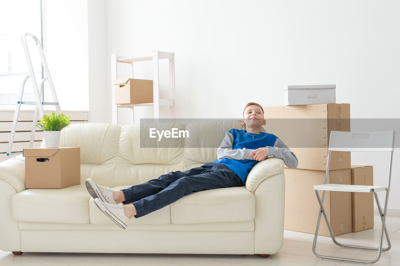 SMILING YOUNG WOMAN SITTING ON SOFA AT HOME