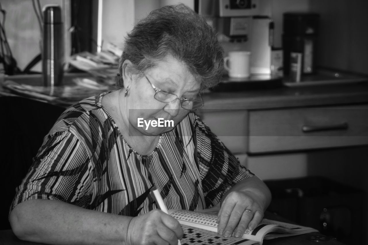 Senior woman writing in newspaper while sitting at home