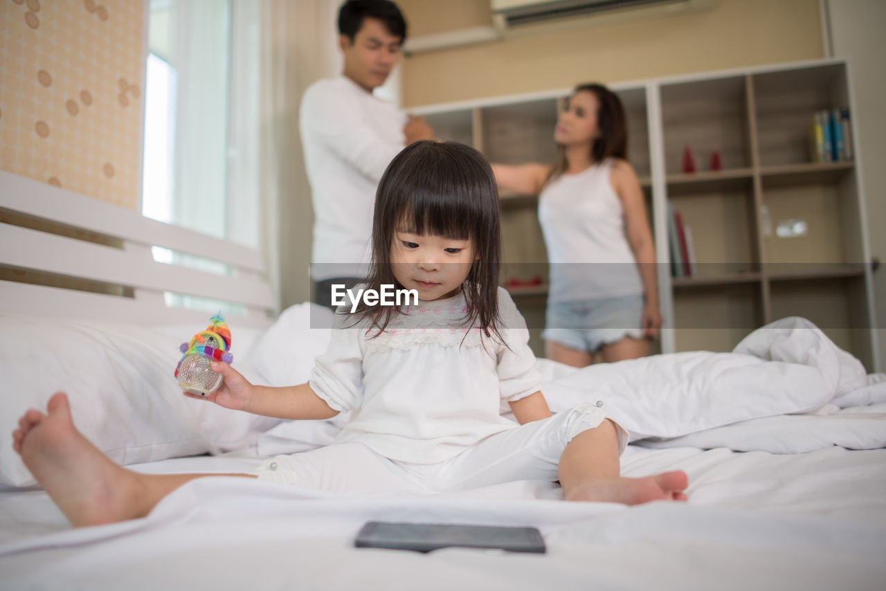 Girl watching video in mobile phone while parents arguing at home