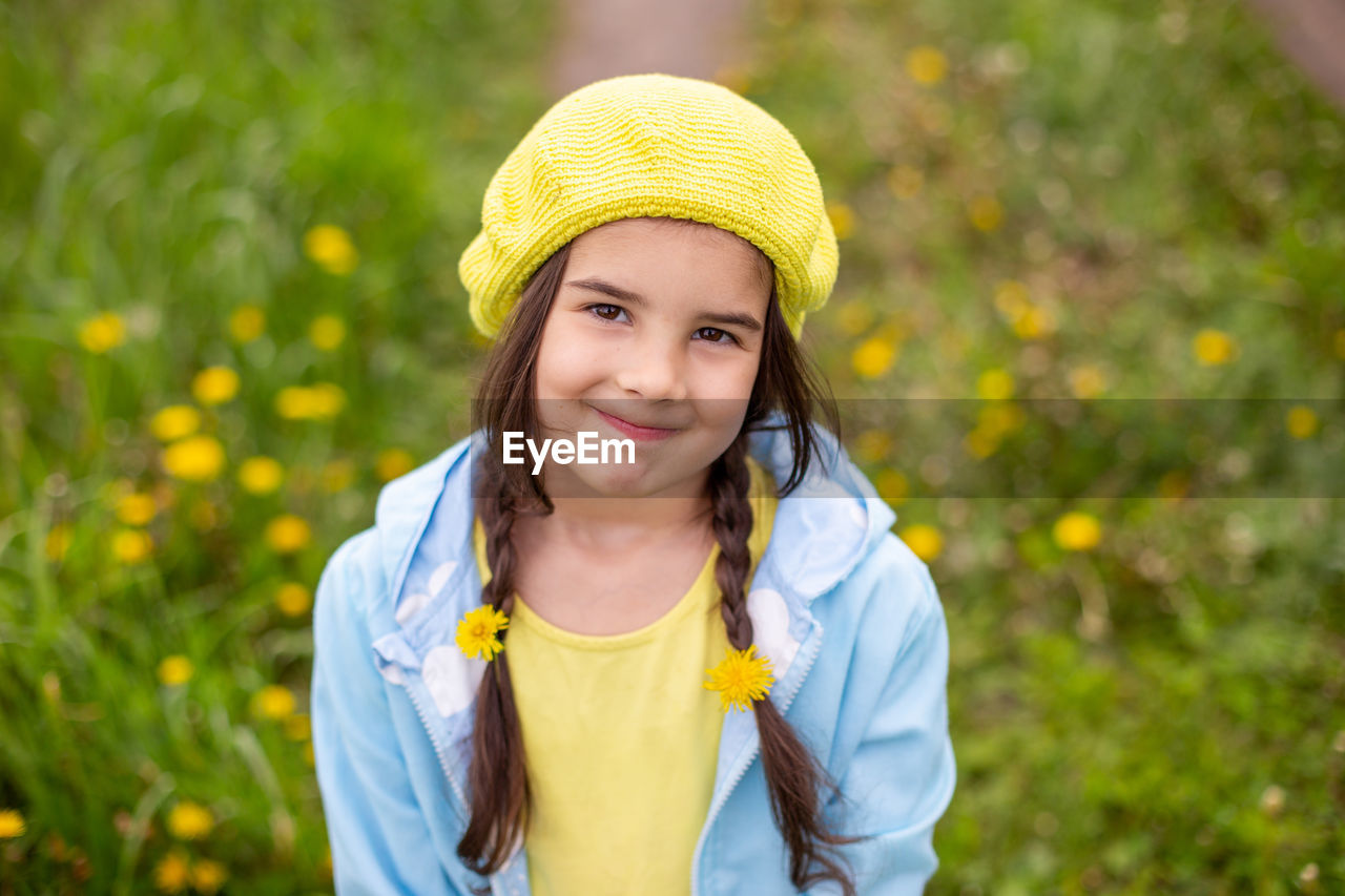 Top portrait of a charming little girl with two pigtails with woven dandelions