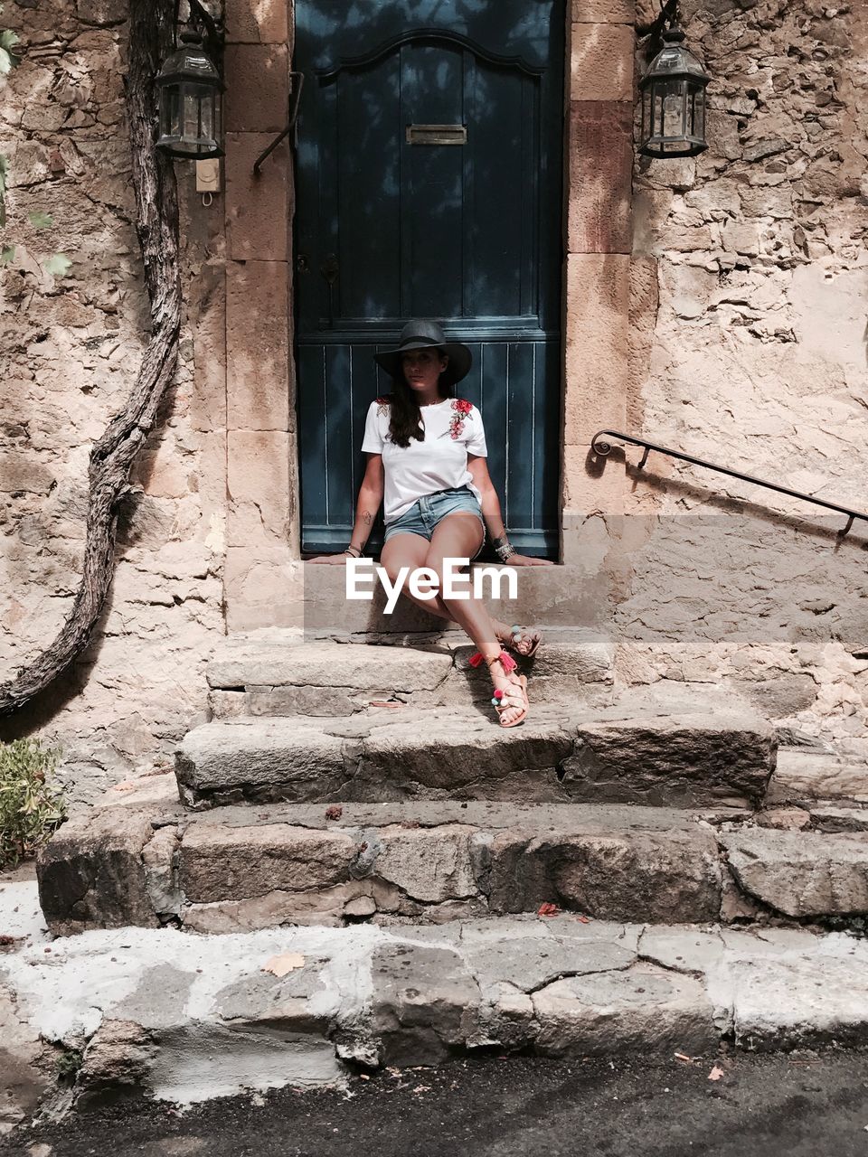 Full length of woman sitting against house