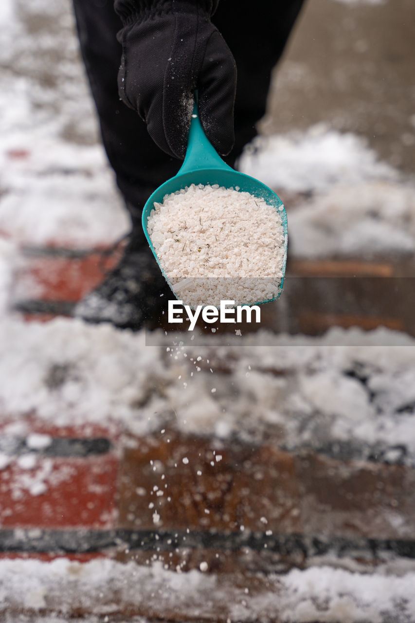 LOW SECTION OF PERSON STANDING ON SNOW COVERED WATER