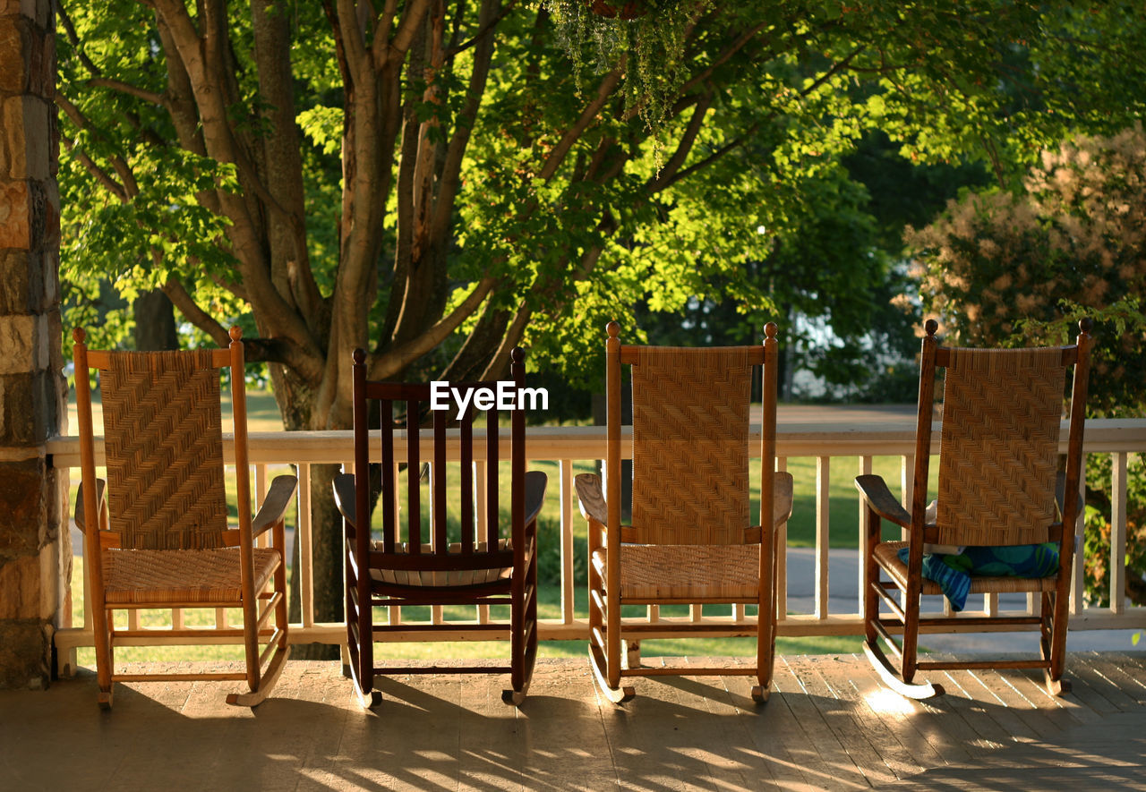 Empty wooden chairs against trees at porch
