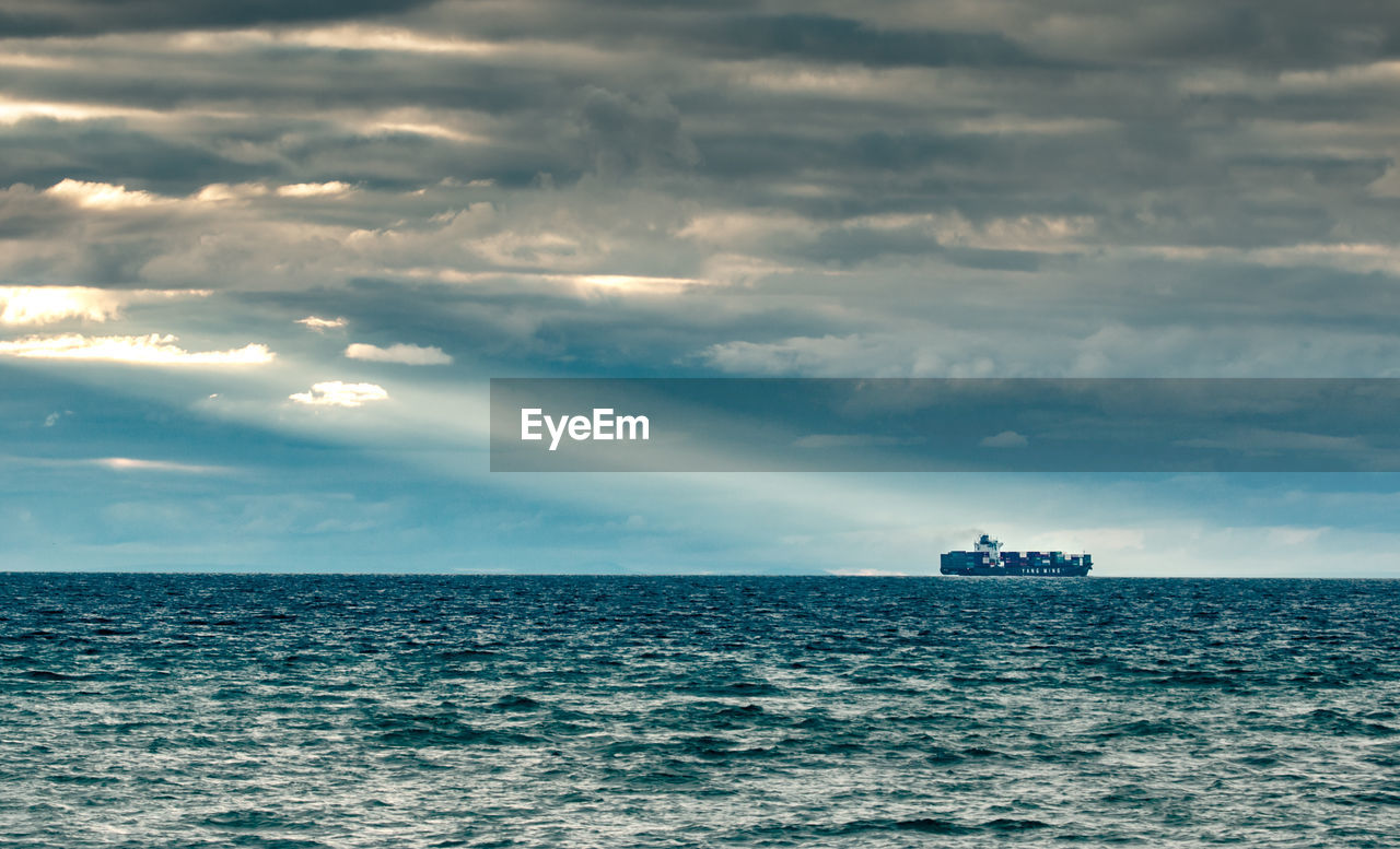 Boat in sea against cloudy sky