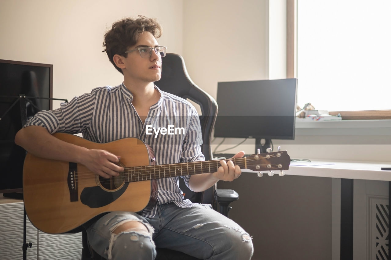 man playing guitar at home