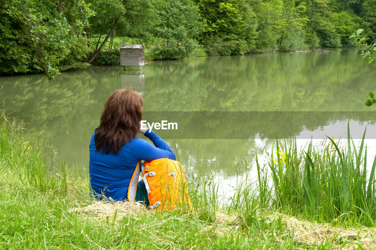 Rear view of woman sitting by lake