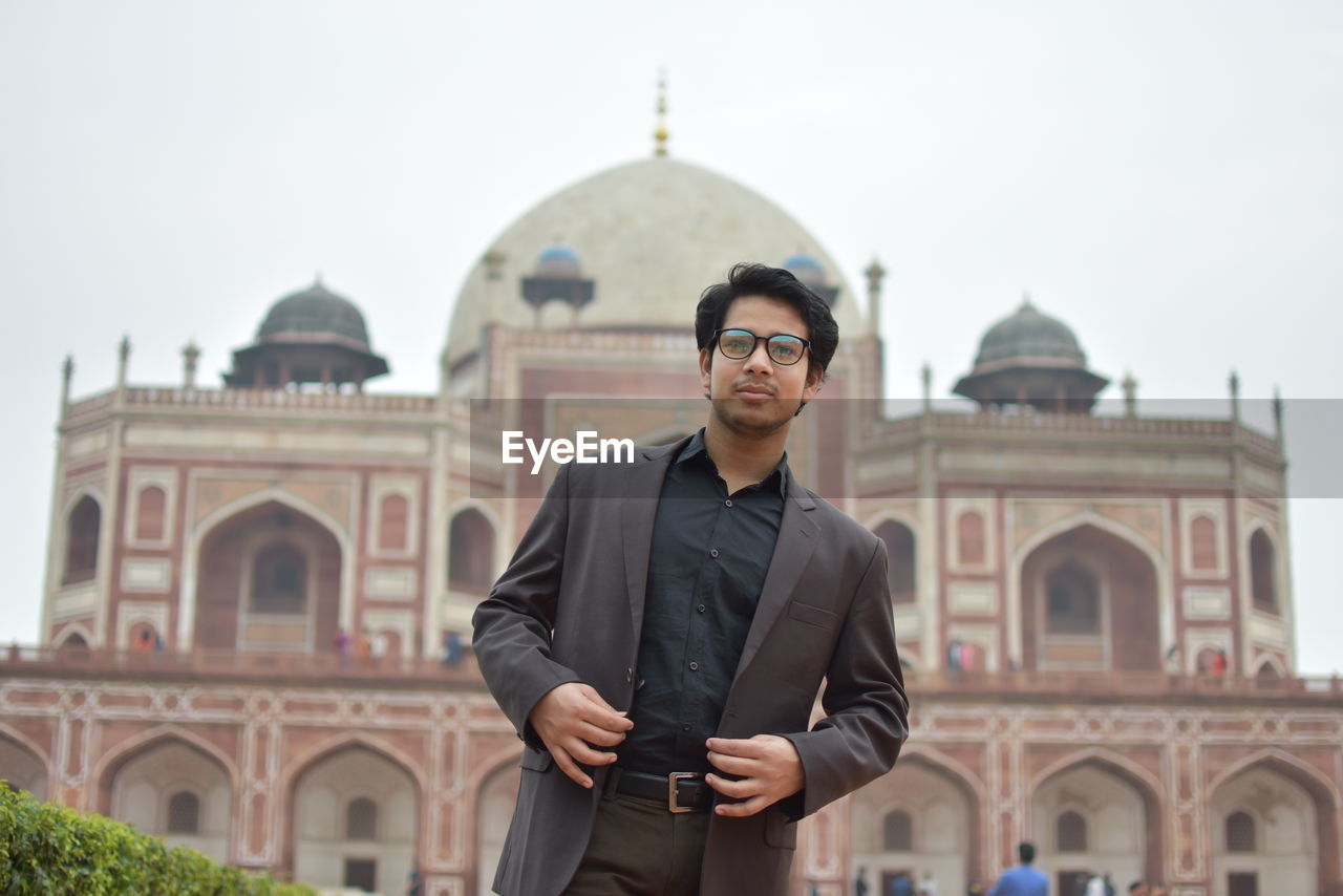 Portrait of man standing against building and sky