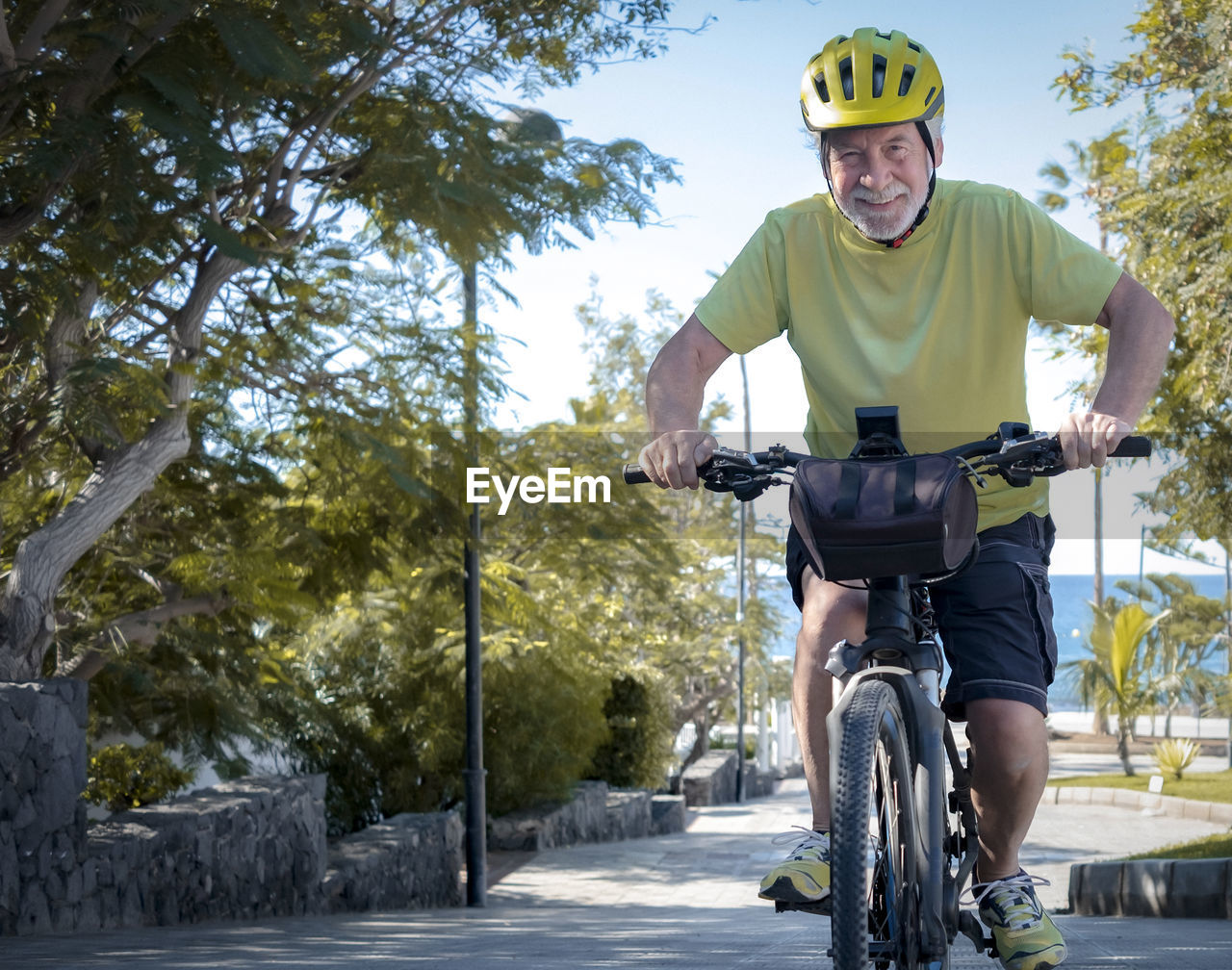 Portrait of smiling senior man riding bicycle outdoors