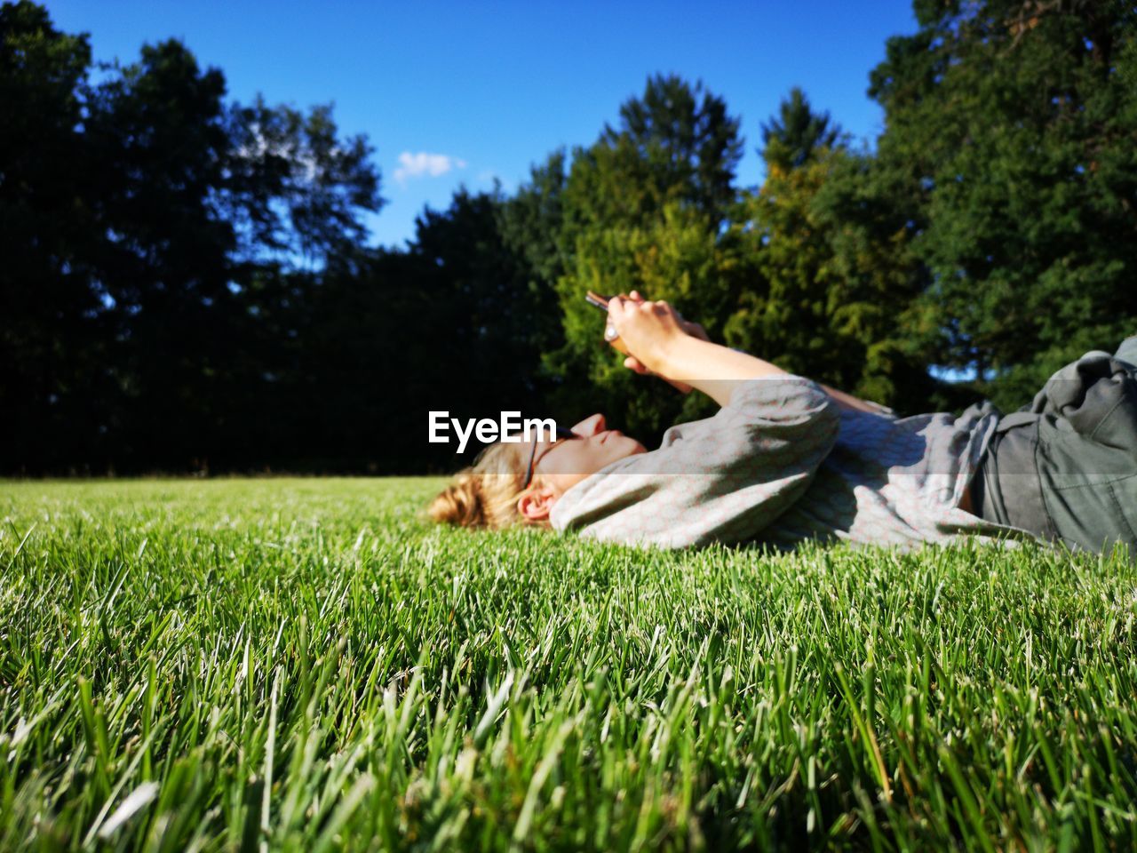 Woman using phone while lying on field