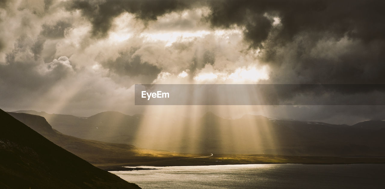 Sunlight streaming through clouds over mountain