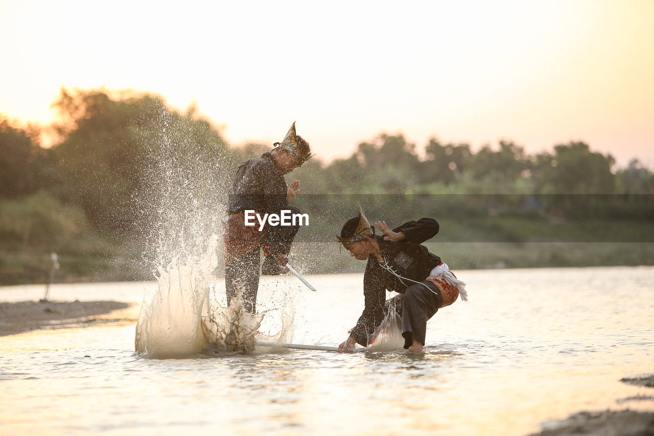 FULL LENGTH OF MAN SPLASHING WATER IN SKY