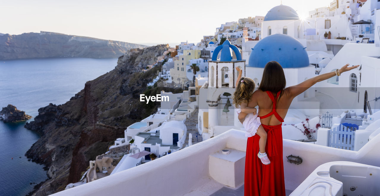 Rear view of mother holding daughter looking at townscape