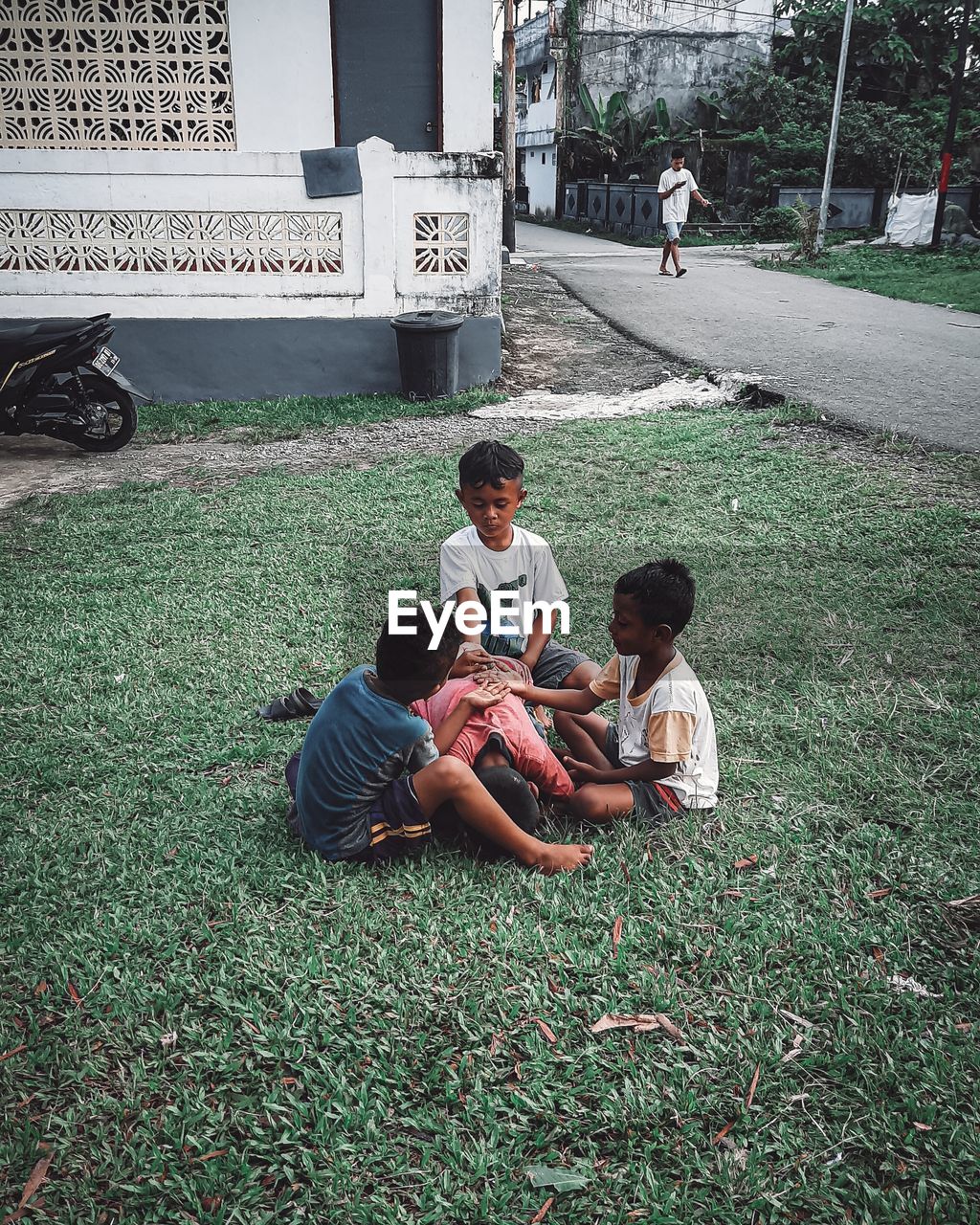 REAR VIEW OF FATHER SITTING ON GRASS