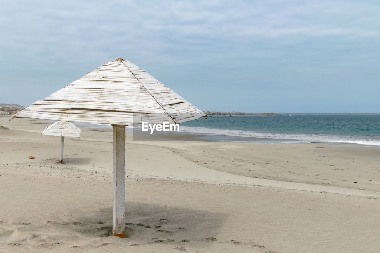 Beach hut on sand against sky
