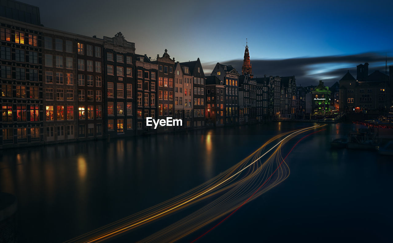 Light trails on road against buildings