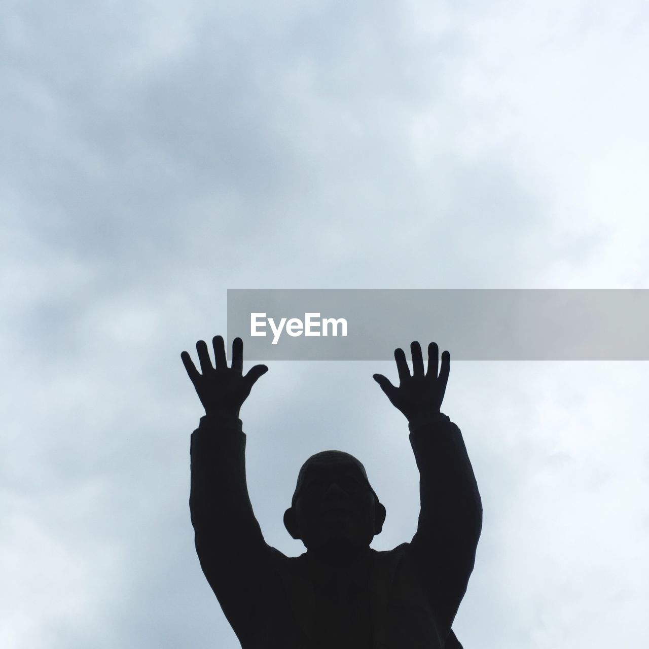 Silhouette man with arms outstretched against the sky