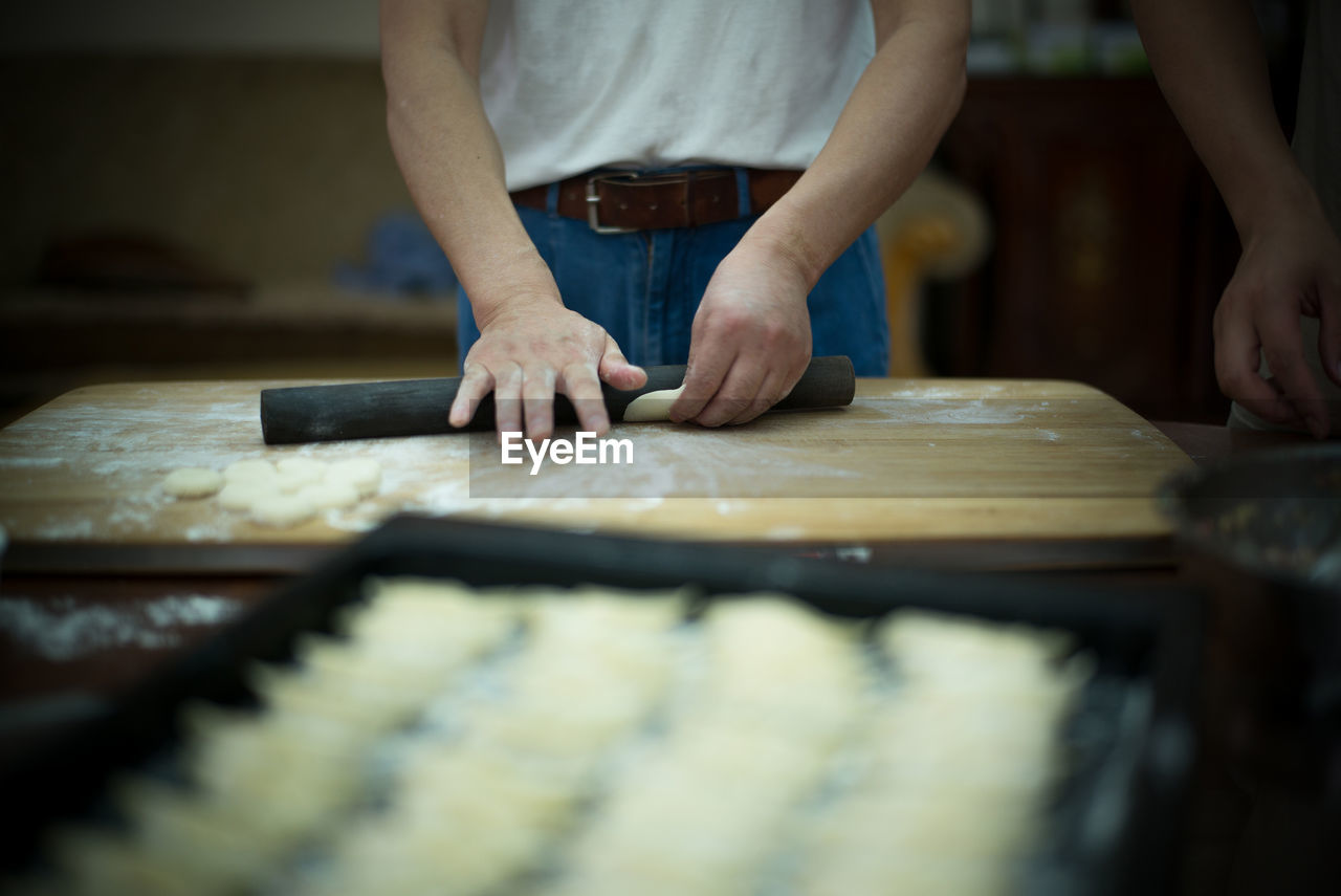 Midsection of man rolling dough at table