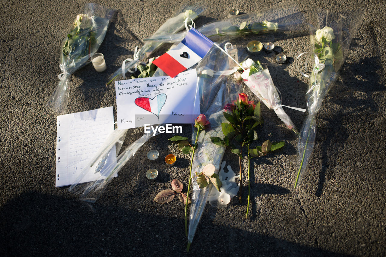 High angle view of french flag with bouquets on road after terrorist attack