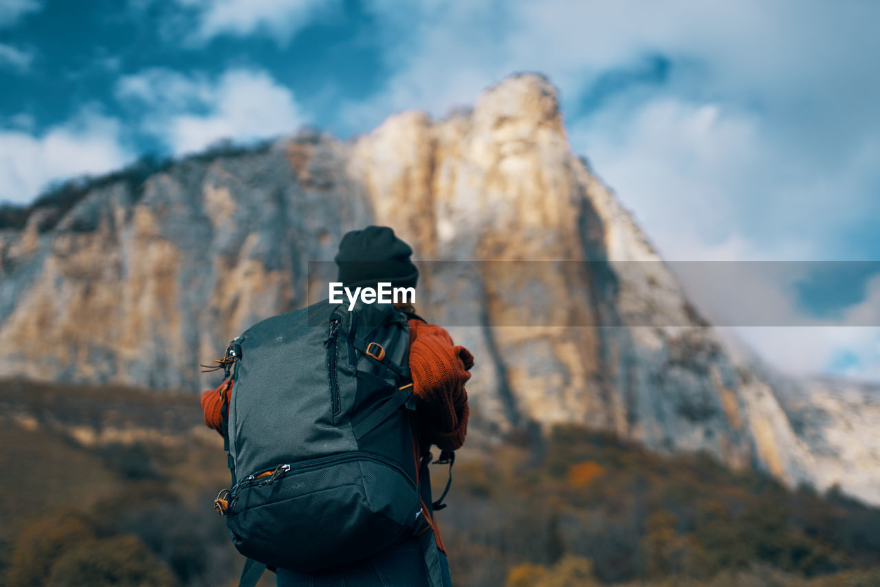 REAR VIEW OF MAN STANDING ON MOUNTAIN