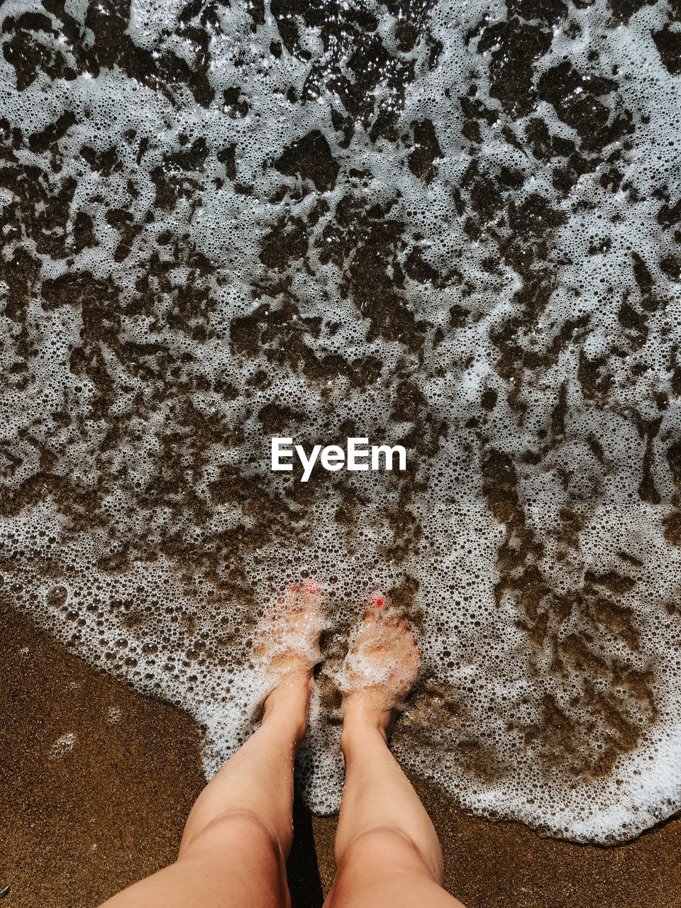 low section of woman standing on sand