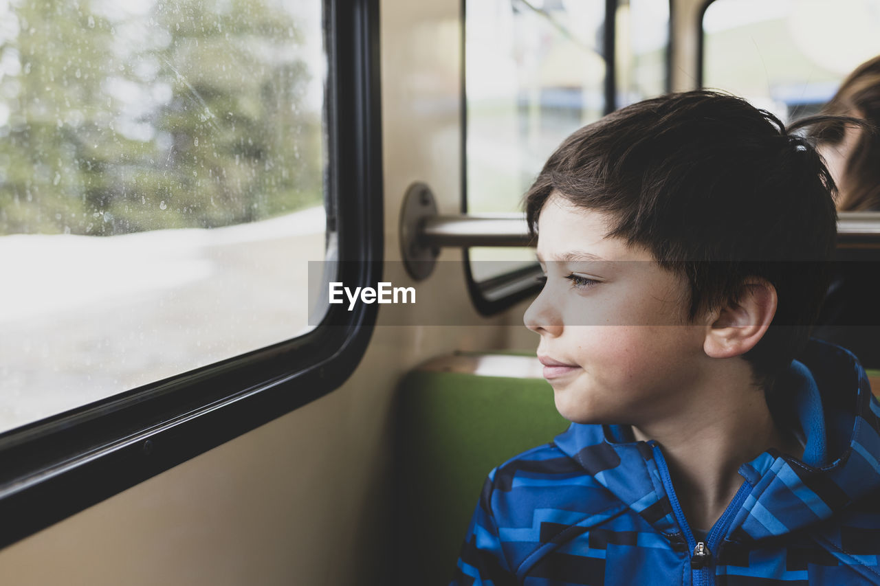 Boy looking away through window while sitting in bus