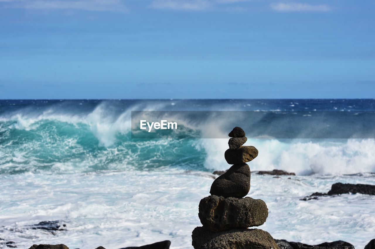 Stack of rocks in sea against sky