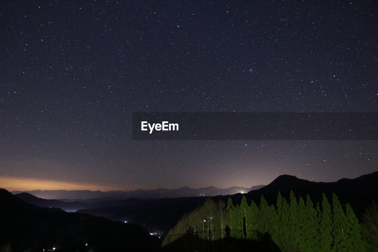 Scenic view of mountains against star field in sky at night