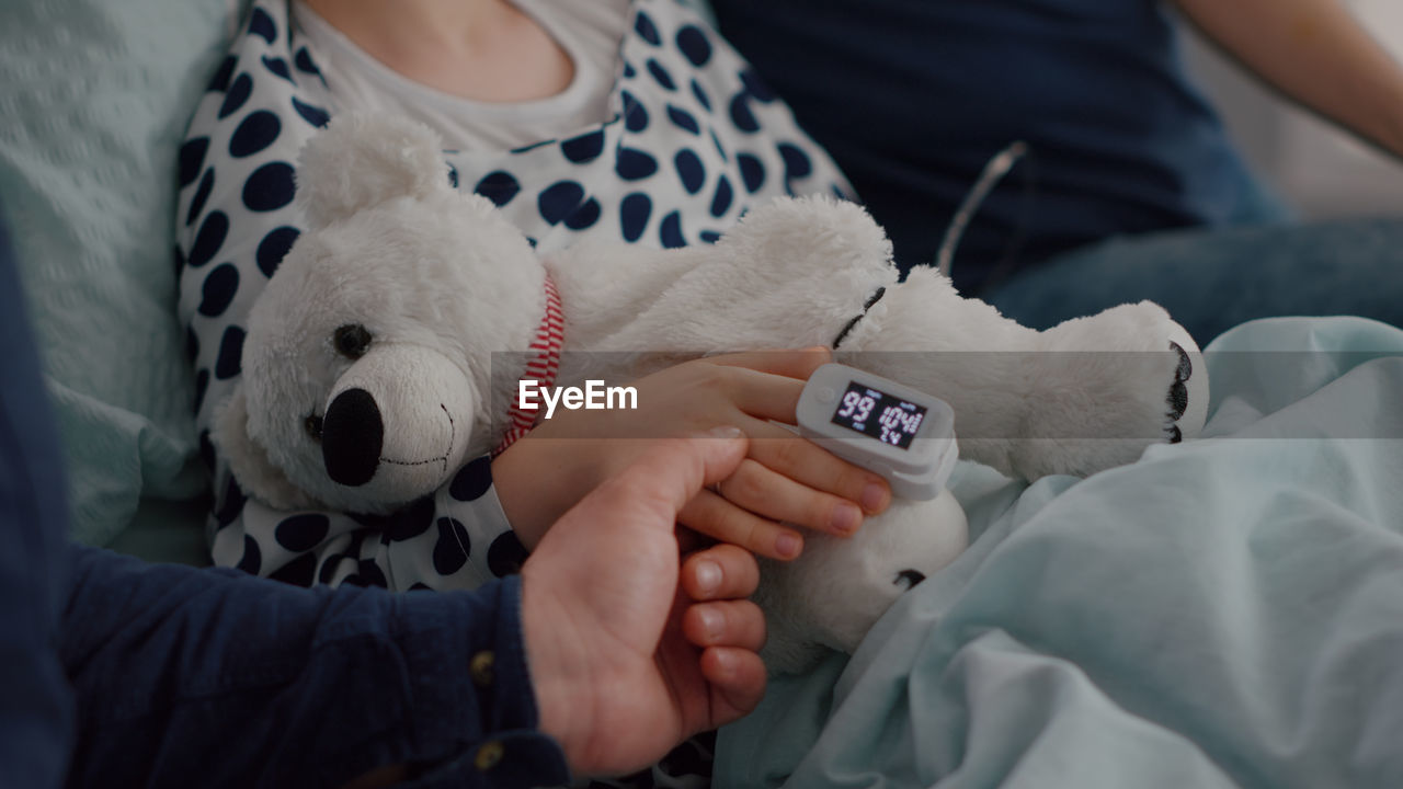 Midsection of woman with stuffed toy on bed