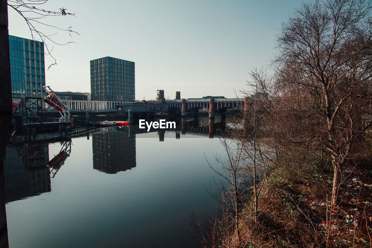 reflection, architecture, water, built structure, building exterior, sky, nature, city, morning, tree, building, cityscape, bare tree, urban area, river, no people, plant, outdoors, skyline, clear sky, travel destinations, winter, dusk, day, waterway