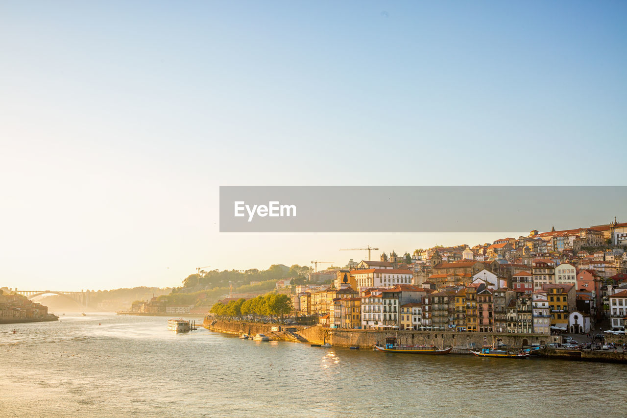 Scenic view of the river in porto by buildings during sunset.