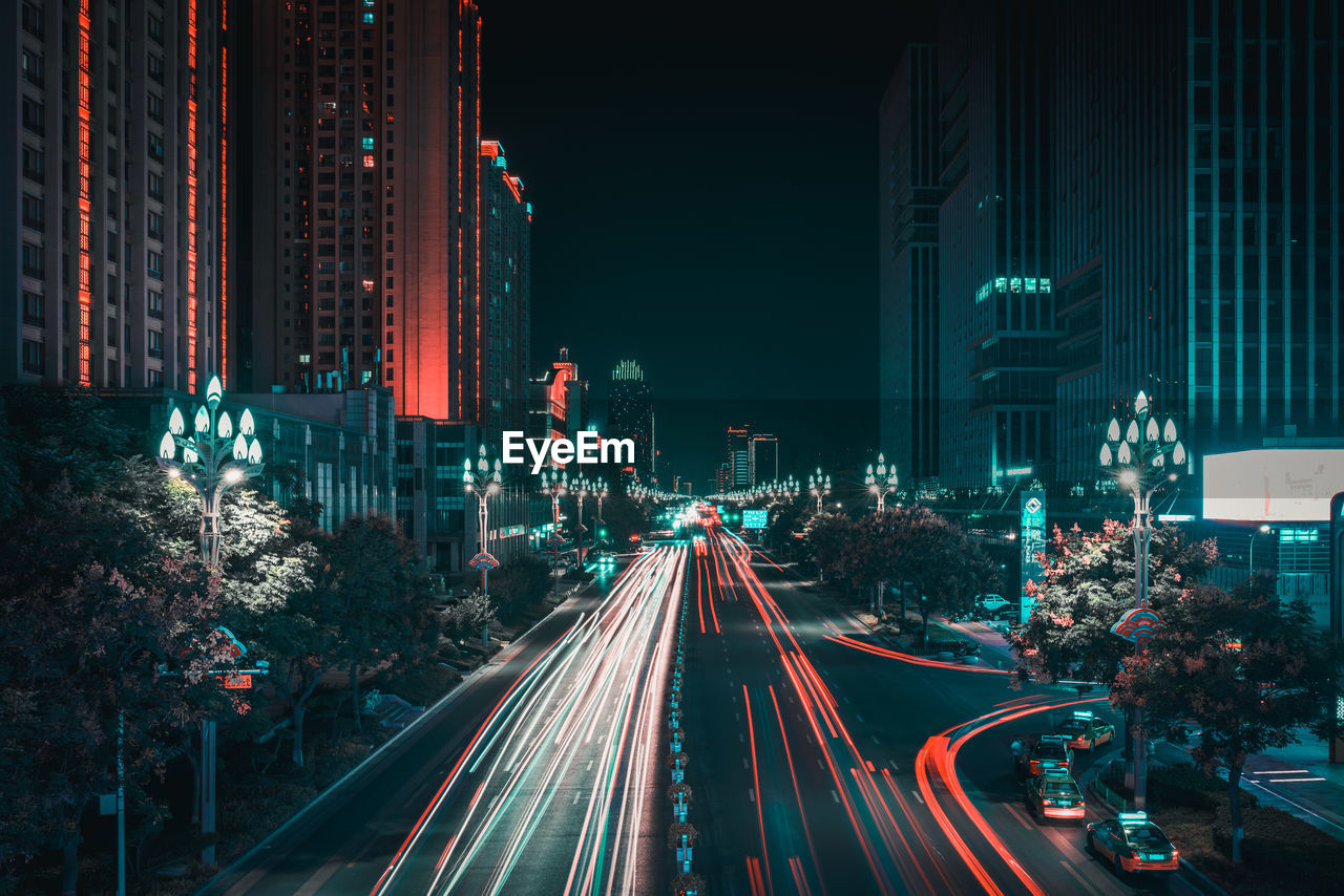 High angle view of light trails on street amidst buildings at night