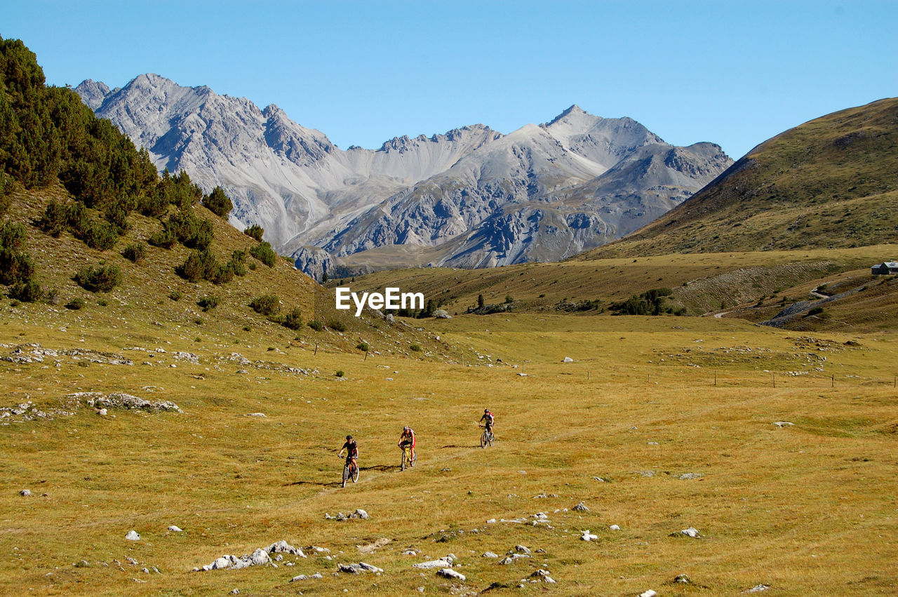 PEOPLE ON LANDSCAPE AGAINST MOUNTAINS