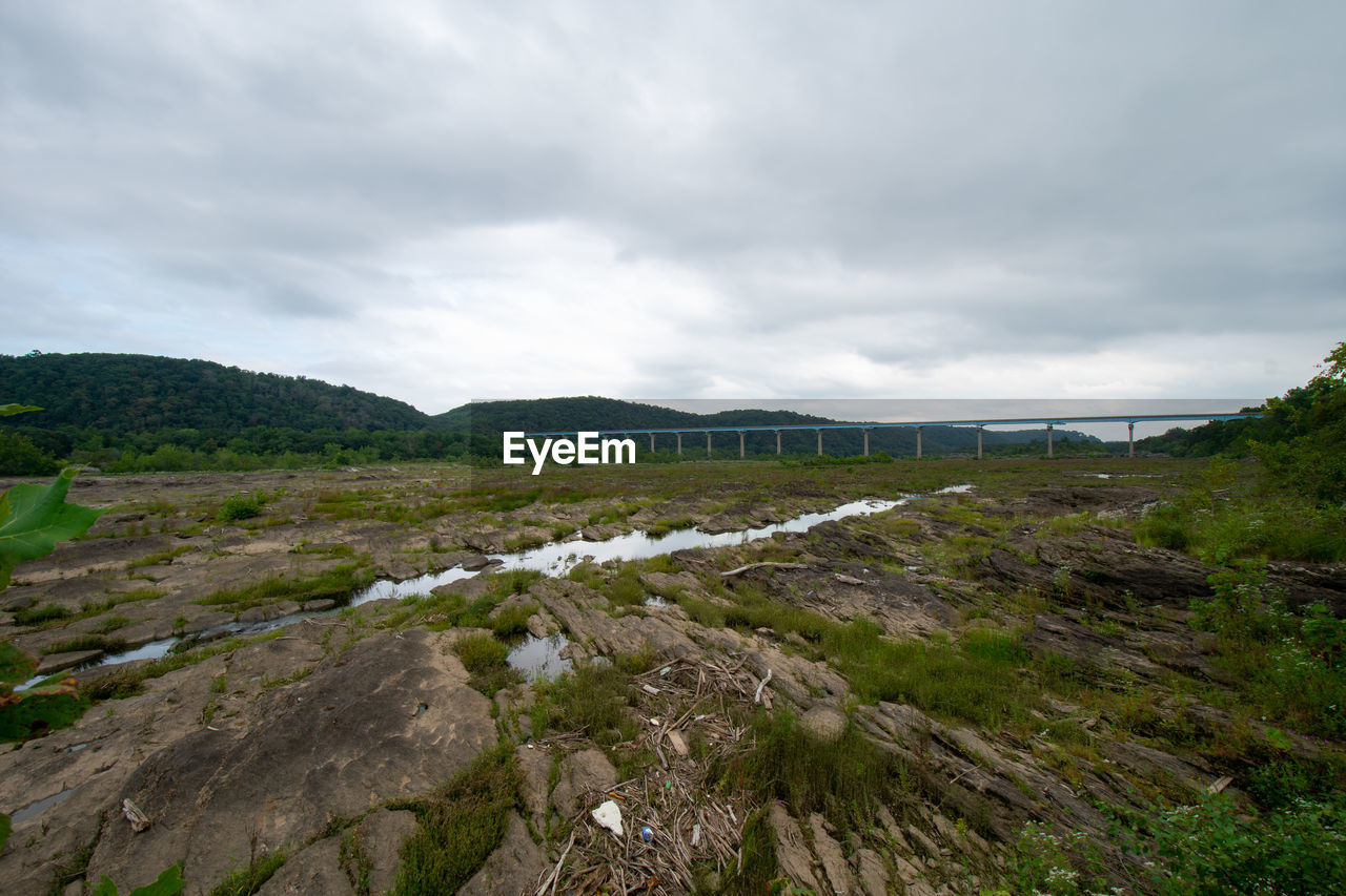 A huge sprawling landscape covered in rock formations and plants with the norman wood bridge behind 