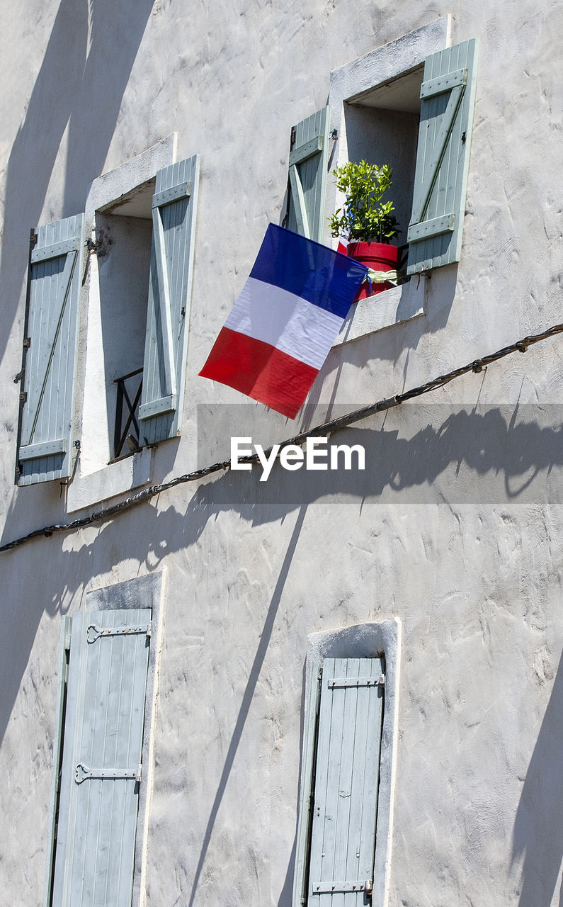 The facade of the building with the flags of france in the window.