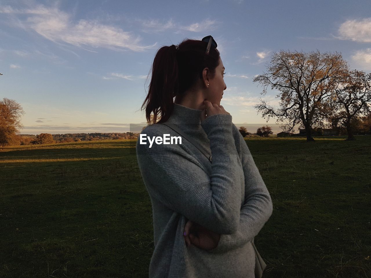 Young woman looking away while standing on land against sky