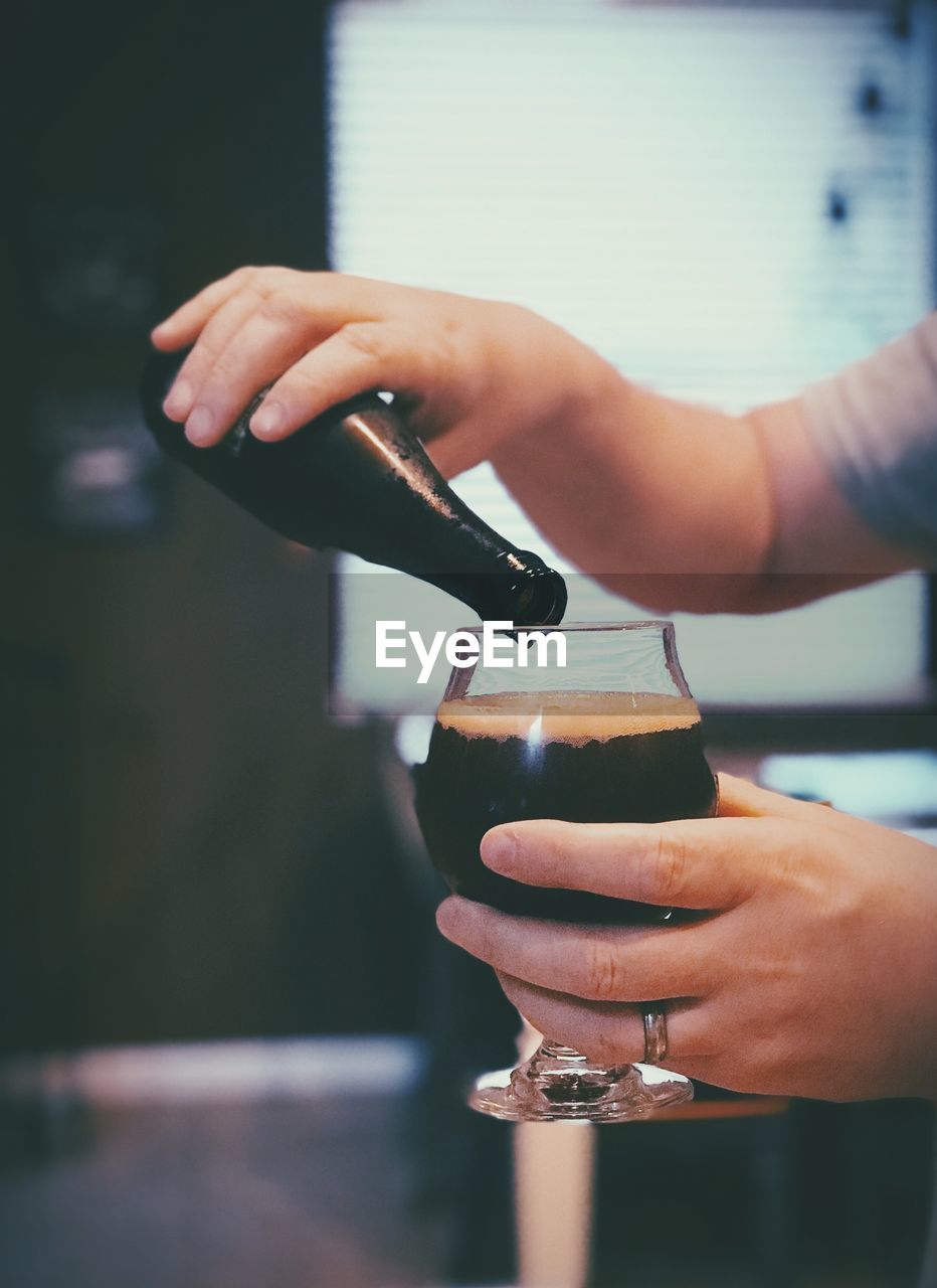Close-up of hand pouring stout beer drink