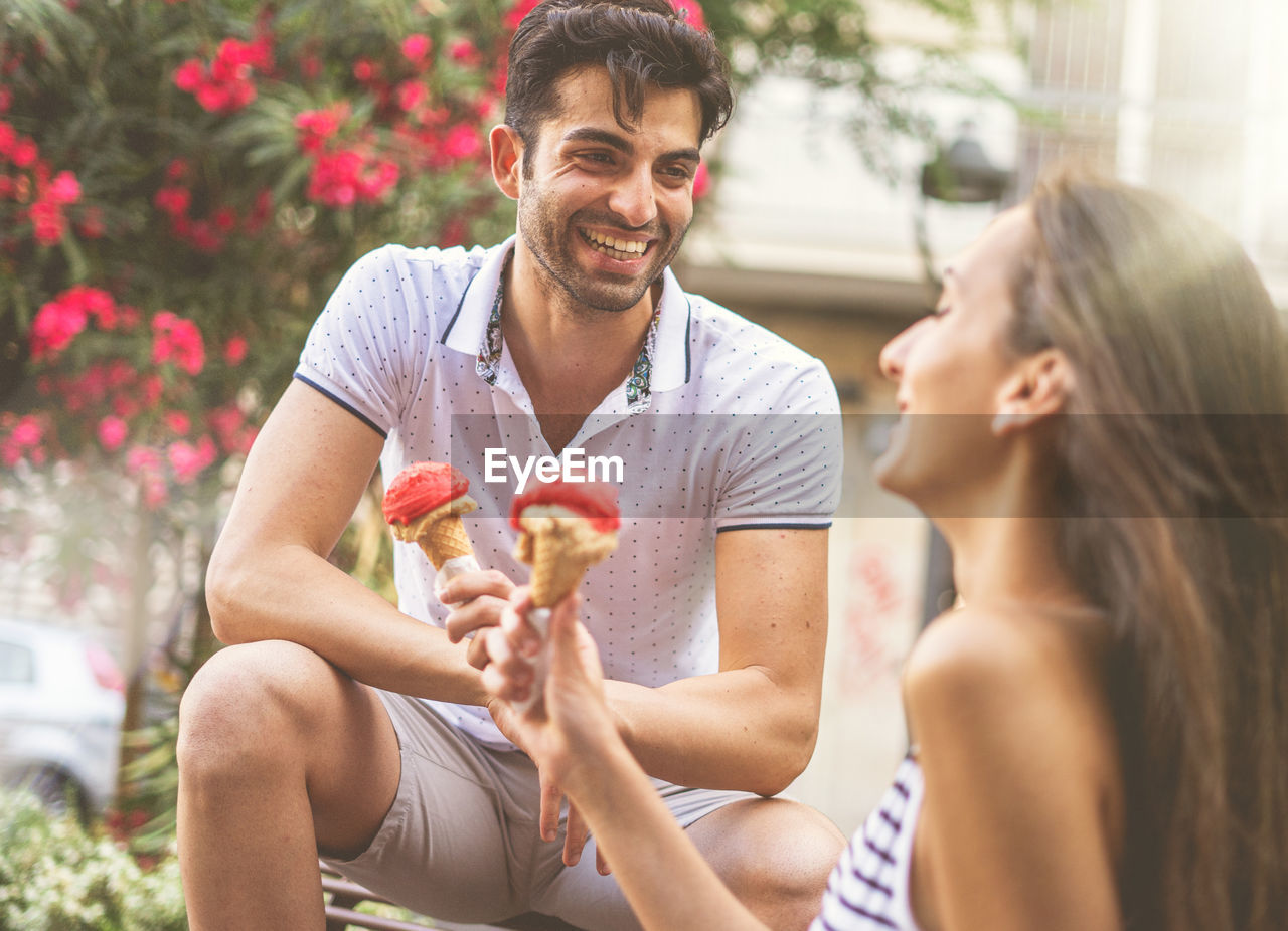 Happy couple holding ice cream cones in park