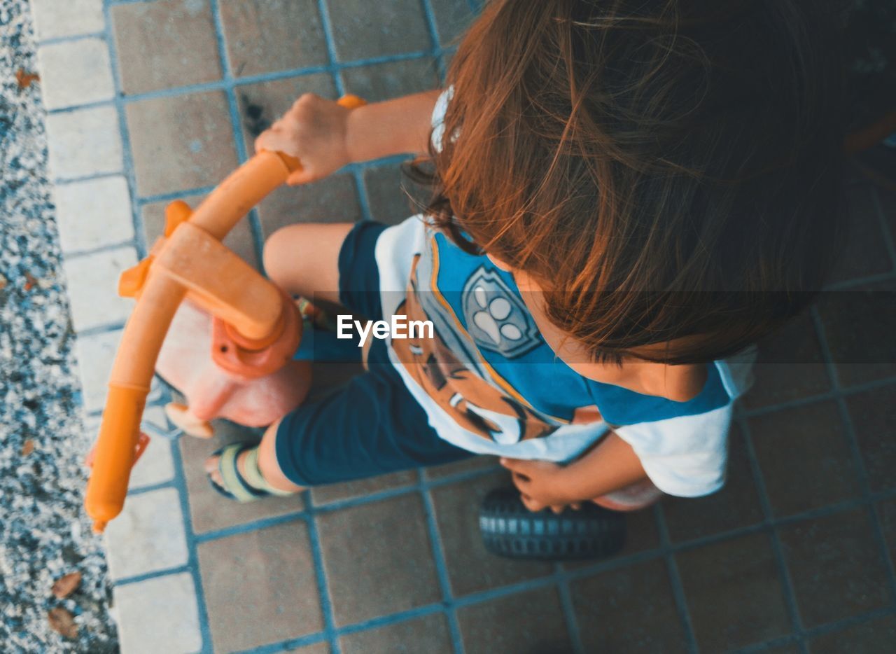 High angle view of boy sitting on tricycle