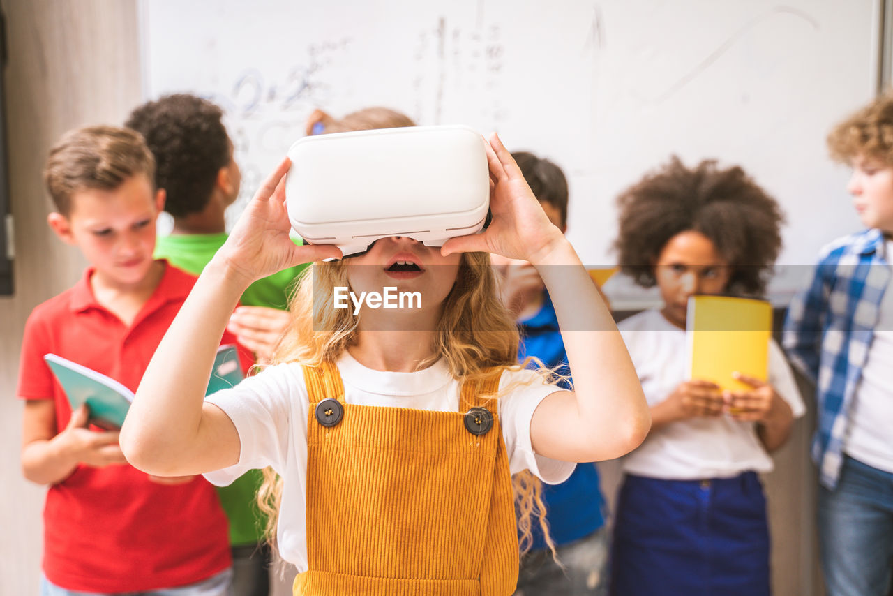 Cute girl using virtual reality simulator at classroom