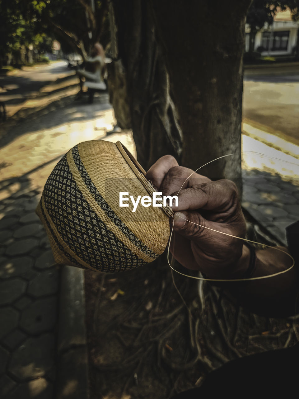 Close-up of man weaving pot by tree