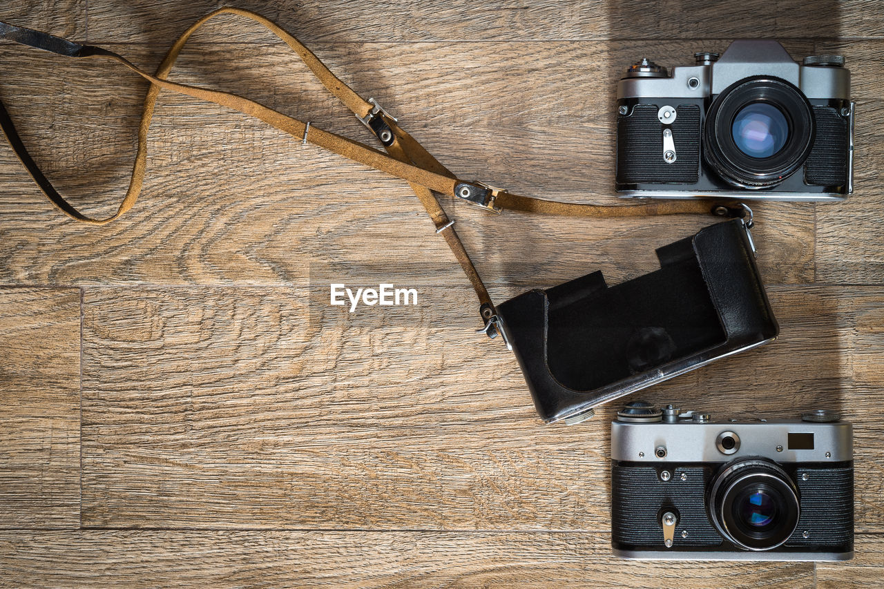 Old retro style film photo camera and leather case on wooden background  with space for copy