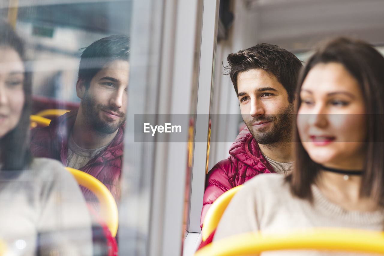 Uk, london, portrait of smiling young man in bus looking out of window