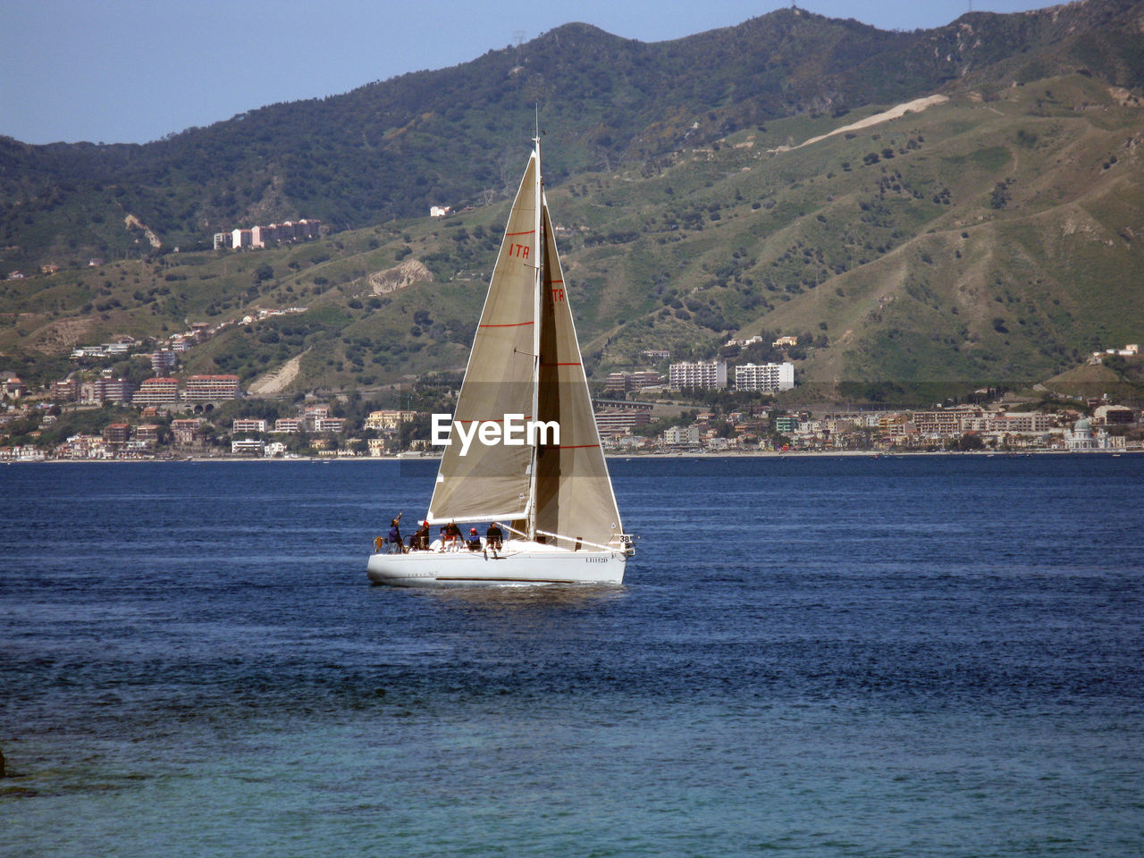 SAILBOAT SAILING ON SEA AGAINST MOUNTAIN