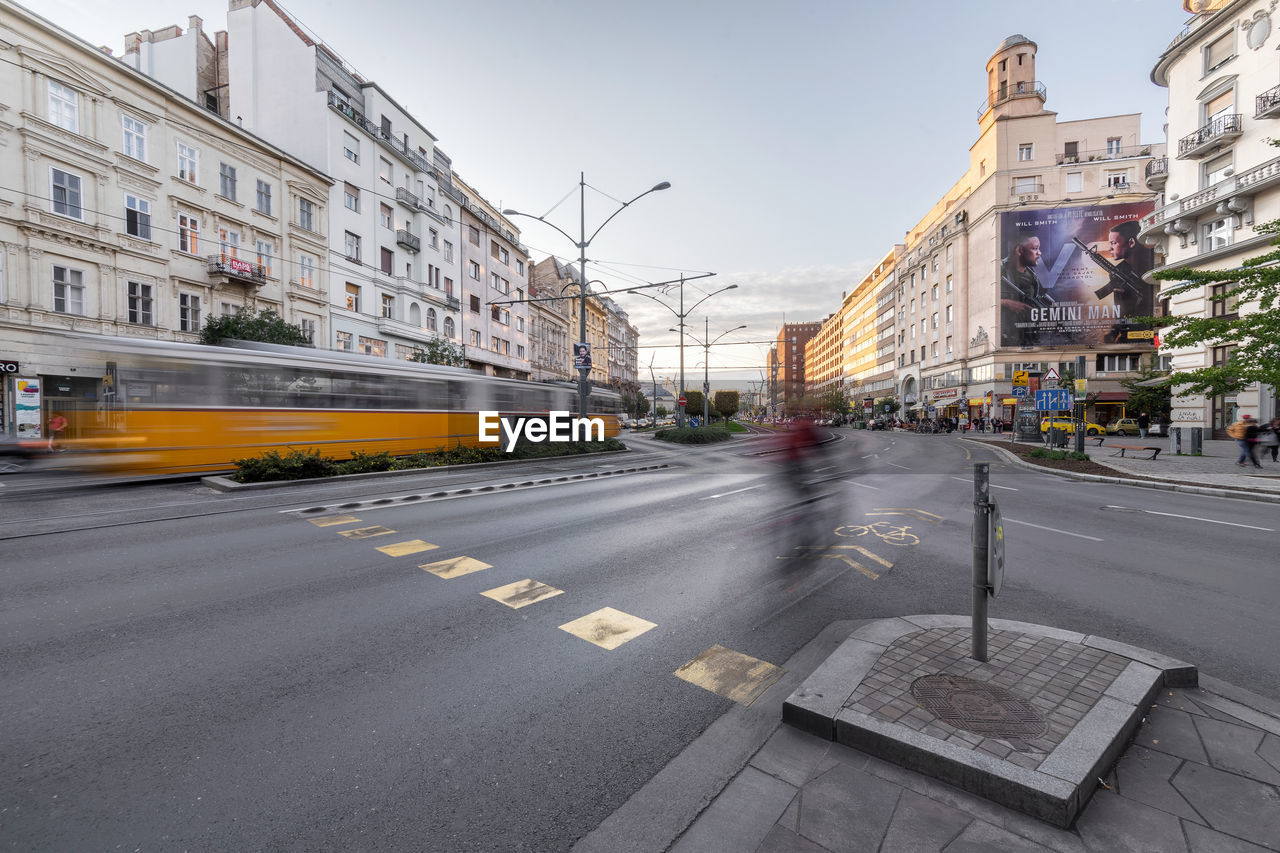 TRAFFIC ON ROAD BY BUILDINGS AGAINST SKY