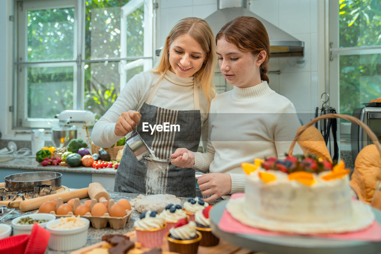 Mother and daughter working together happily to make sweets on holiday.