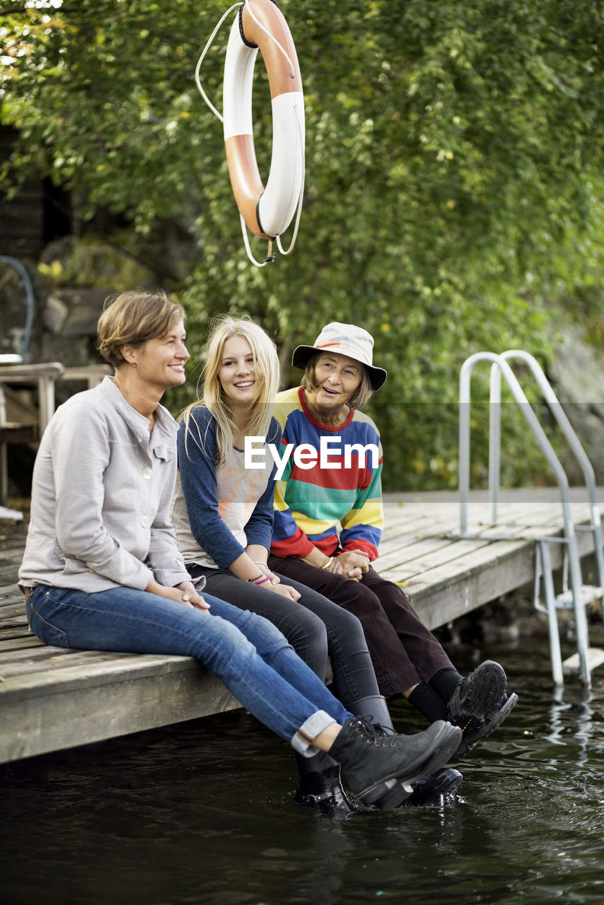 Three generation females sitting on pier